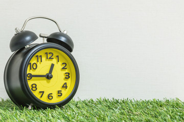 Closeup black and yellow alarm clock for decorate show a quarter to twelve o'clock or 12:45 p.m. on...