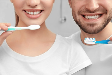 Young happy couple brushing teeth in bathroom