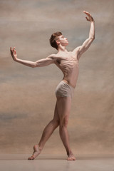 Obraz premium The male ballet dancer posing over gray background