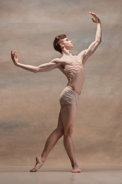 The male ballet dancer posing over gray background