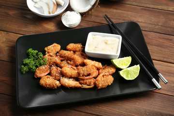Plate with delicious coconut shrimps on table