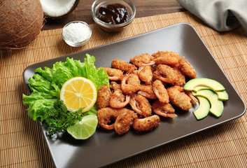 Plate with delicious coconut shrimps on table