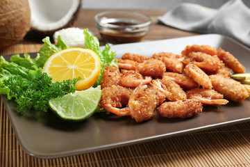 Plate with delicious coconut shrimps on table