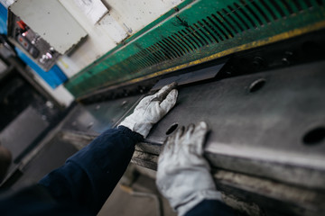 Metallurgy heavy industry. Factory for production of heavy pellet stoves and boilers. Worker hands close up. Extremely dark conditions and visible noise. Focus on foreground.