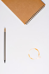 top view of notebook with pencil and coffee stain isolated on white