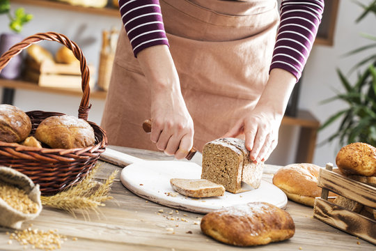 Female hands cutting whole wheat bread