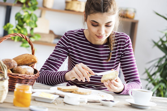 Young Woman Eating Bread With Butter