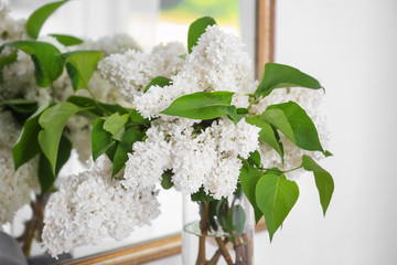 Beautiful bouquet of lilac in vase near mirror
