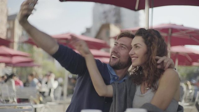 Couple at sidewalk cafe posing for selfie