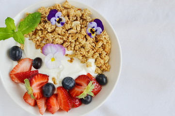 Yogurt with granola and fruits, blueberries, strawberries, cherry, apple, banana, healthy breakfast