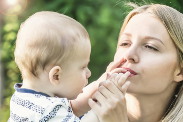 Pretty woman kissing the small fingers of her baby son