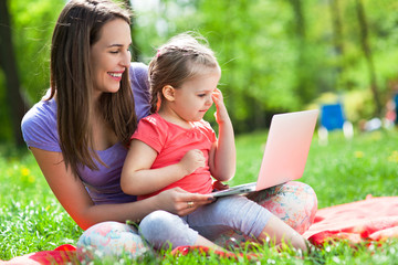 Mother with child using laptop outdoors
