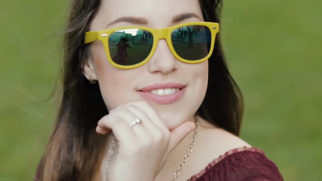 Portrait of young woman sitting on grass in sunglasses