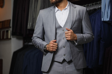Modern young handsome businessman looking and choosing classical suit in the suit shop