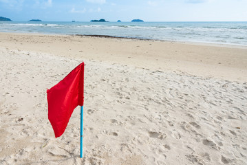 Fototapeta na wymiar Warning sign of a red flag at a beautiful beach with a blue sky at Prao Beach in Trat, Thailand.