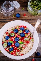 Healthy breakfast bowl oatmeal with fresh blueberries, pomegranate, mint, chia, flax and pumpkin seeds