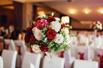 Bouquet of red and white roses stands in the middle of dinner table