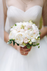 Bride holds white bouquet in her tender arms