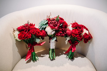 Three red wedding bouquets stand on white chair