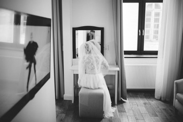 Bride writes something sitting at a dressing table