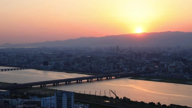 Aerial view time lapse of Osaka City Central business and Yodo River with its bridges at sunset colors. Osaka Skyline from Kita ward of Japan.
