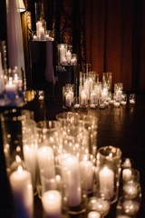 Shiny candles in tall vases stand on the floor