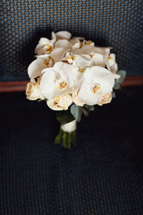 Wedding bouquet made of orchids lies on blue chair