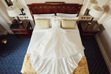 Elegant wedding dress lies on bed in the hotel room