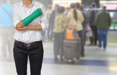 Injured woman with green cast on hand and arm on motion blur in the subway station background, body injury concept