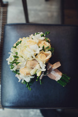 White wedding bouquet lies on leather chair