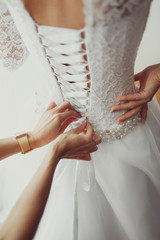 Woman fixes corset on bride's back