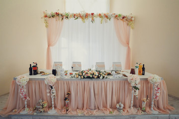 Dinner table for newlyweds covered with pastel pink cloth and white flowers