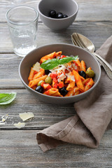 Penne Pasta in tomato sauce with olive on a wooden boards