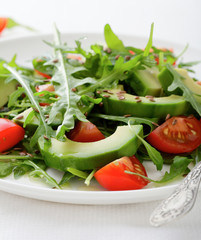 Salad with avocado, cherry tomatoes and arugula closeup