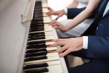 Fototapeta premium Bride and groom play on white piano