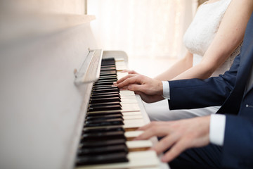 Fototapeta premium Bride and groom play on white piano
