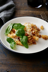 Pasta with a bolognese beef sauce and basil on white plate