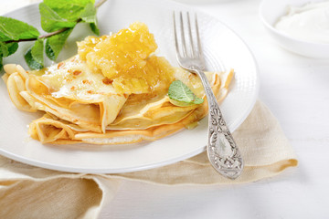 Crepe with honey and sour cream on a plate