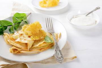 Pancakes with honey and sour cream on a plate
