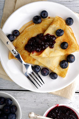 Crepes with jam and forest berries on a plate