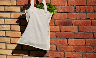 Linen Bag with Fresh Lettuce Salad against the background of a brick wall