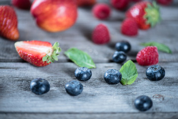 Close-up view of fresh tasty berries with green leaves on wooden table