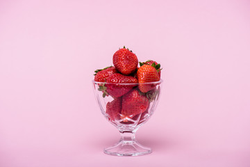 red delicious fresh strawberries in glass bowl isolated on pink