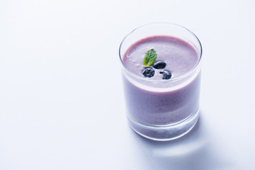 close up of fresh smoothie with blueberries and mint leaf in glass