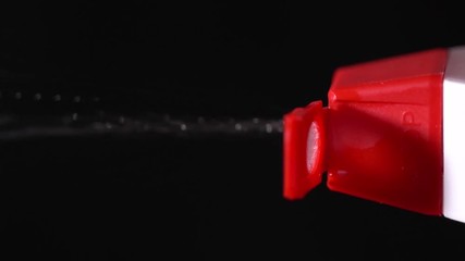 Closeup of red bottle spraying on the black background