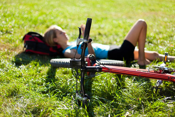 Obraz premium Young cyclist enjoying relaxation lying in the fresh green grass