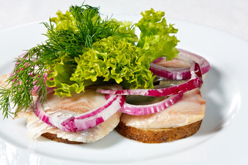 Salted herring fish fillet in the potatoes with onions and herbs