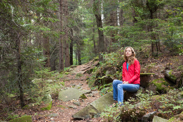 Naklejka na ściany i meble Hiker woman sitting on a halt in stones among the forest