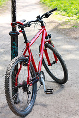 Fototapeta na wymiar Red Bike standing near the pillar on the bike trail