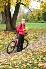 Fototapeta premium Young girl cyclist with bike enjoy vacation in autumn park
